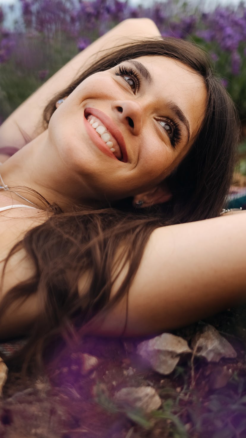 Smiling young woman lying in lavender. Aries, Gemini, Cancer, and Sagittarius zodiac signs will have...