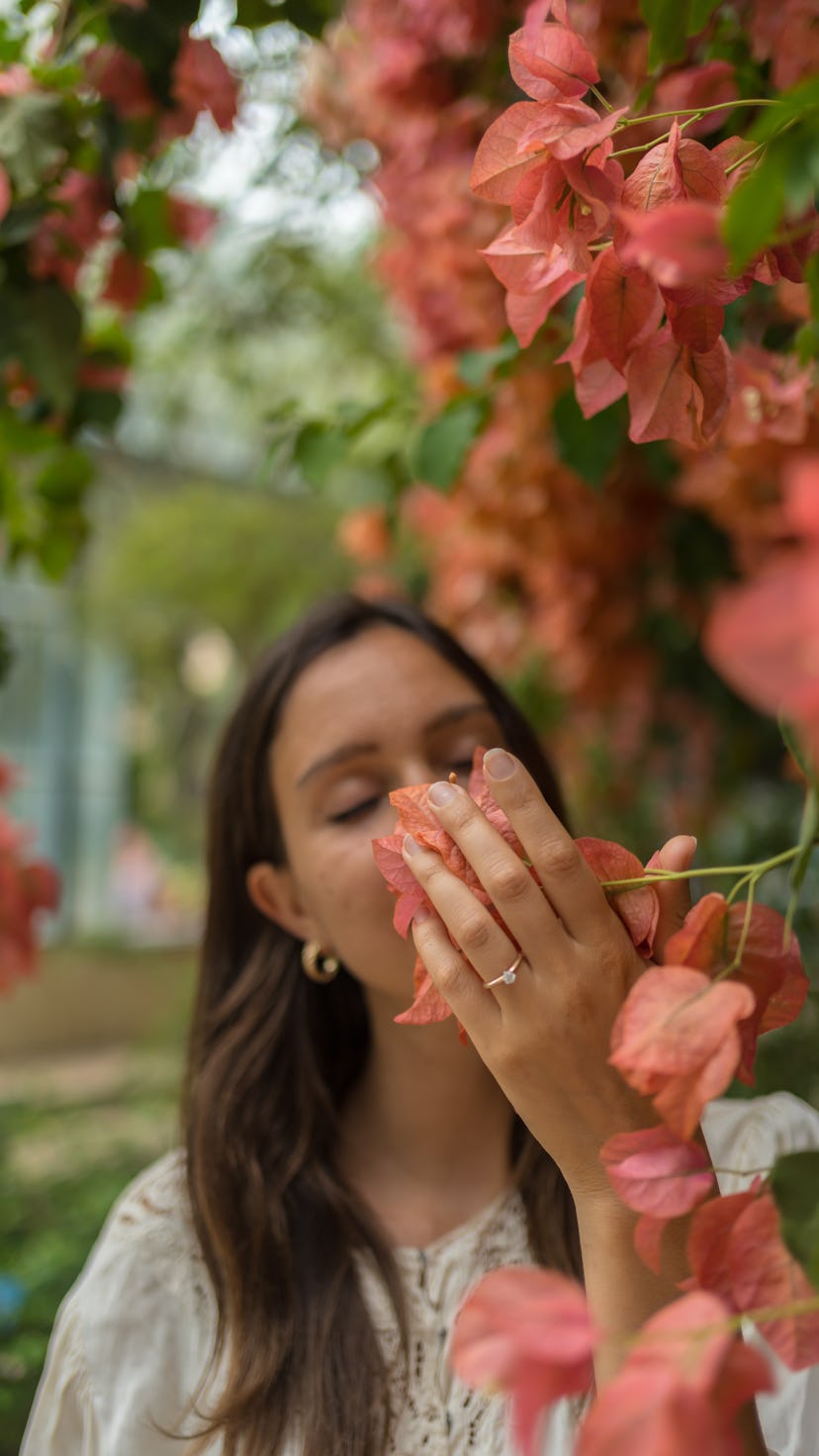 Woman inhales the sweet perfume of the red flowers, on a summer morning. July is full of new opportu...