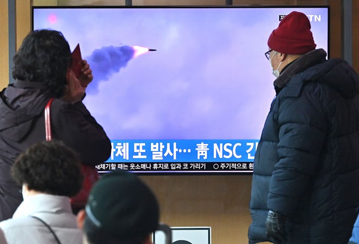 People watch a television screen showing a news broadcast with file footage of a North Korean missil...