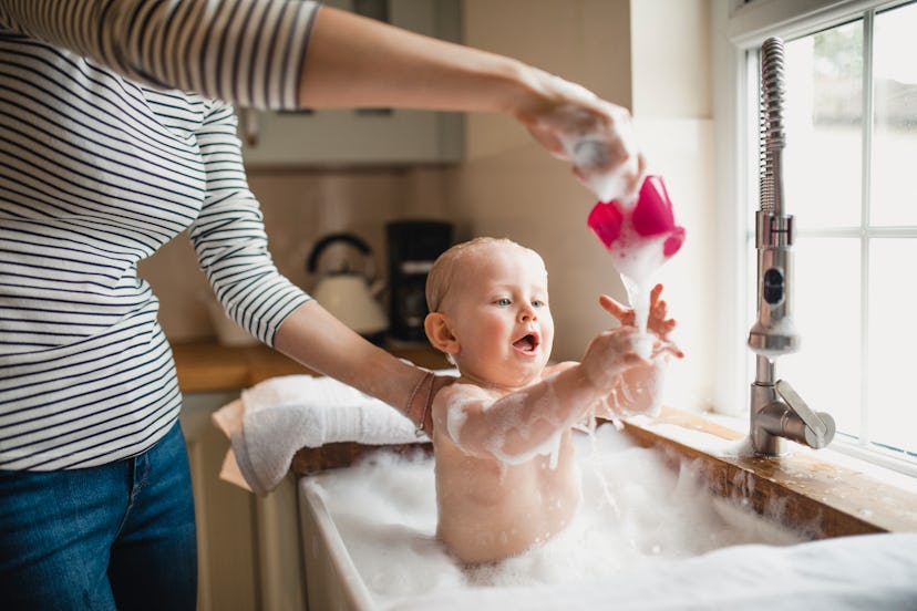 baby loving water, getting bathed in kitchen sink