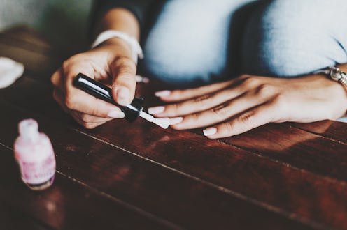 woman applying cuticle oil on her nails
