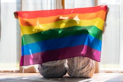 Asian couple Gay celebrating Pride holding up rainbow flag; these lgbtq+ poems are a way to celebrat...