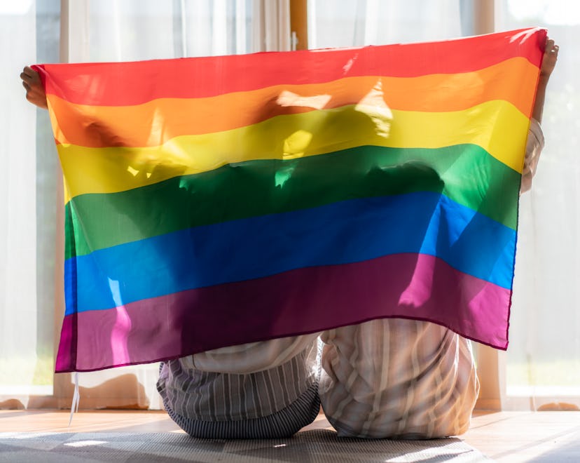 Asian couple Gay celebrating Pride holding up rainbow flag; these lgbtq+ poems are a way to celebrat...