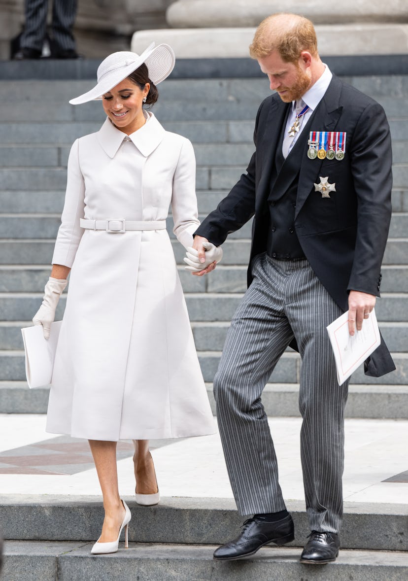 meghan markle wearing a white dior coat dress, wide-brim hat, and matching pumps with prince harry a...