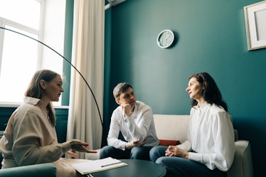 Three people are talking in the office. The psychologist is talking to the patient. Therapist gestur...