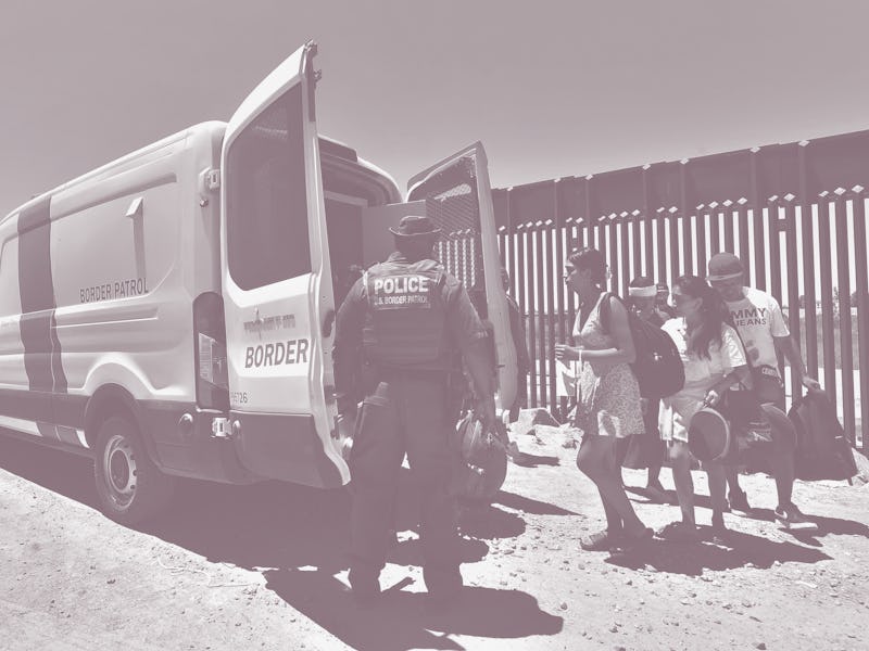 A US Customs and Border Protection (CPB) officer watches as migrants board a Border Patrol van to be...