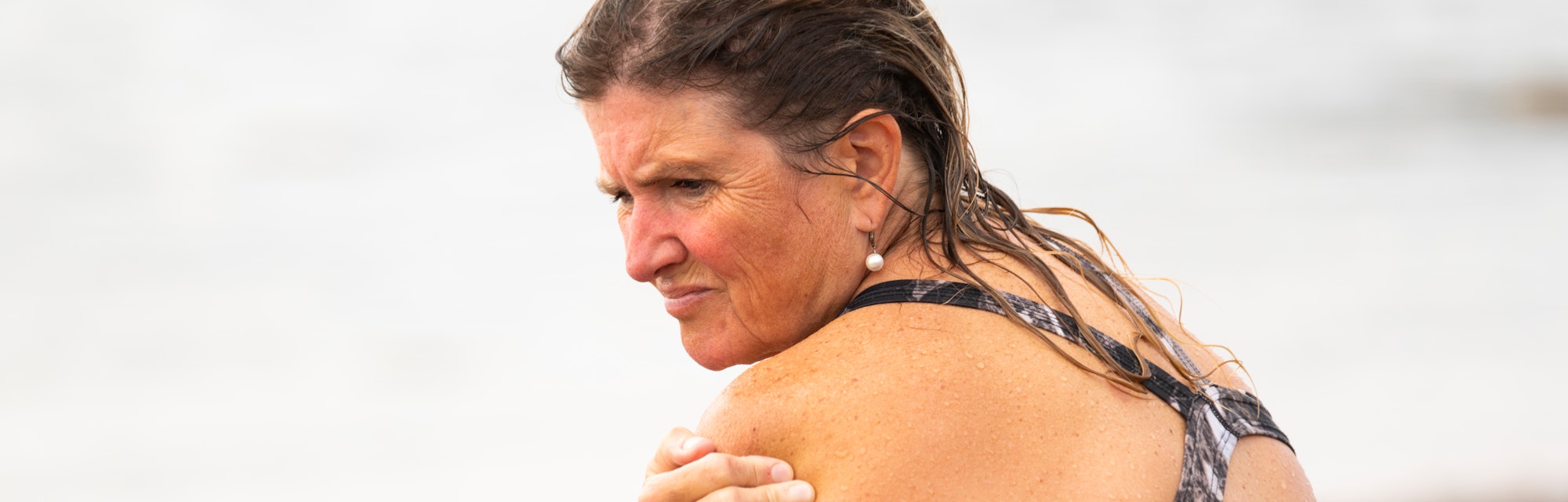 A mature woman with neck and shoulder pain after swimming at the beach