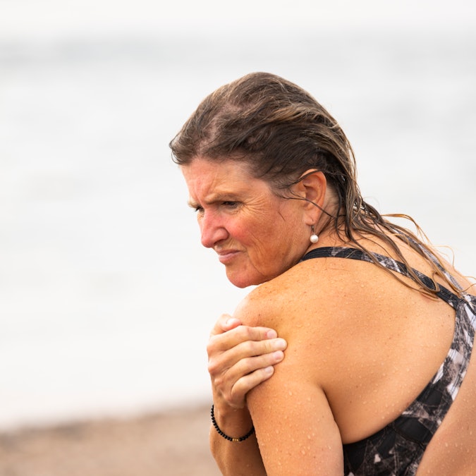 A mature woman with neck and shoulder pain after swimming at the beach
