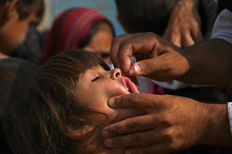 A health worker administers polio vaccine drops to a child during a polio vaccination campaign in Ka...