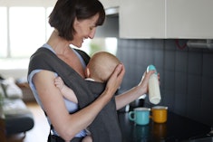 A woman carrying her son in a baby sling