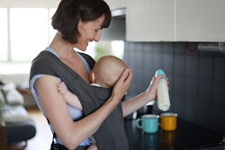 A woman carrying her son in a baby sling