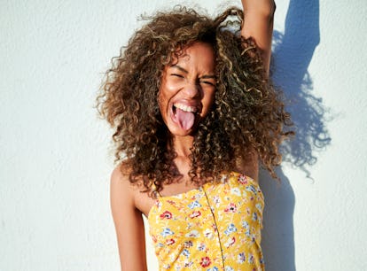 Portrait of woman sticking out tongue in front of white wall