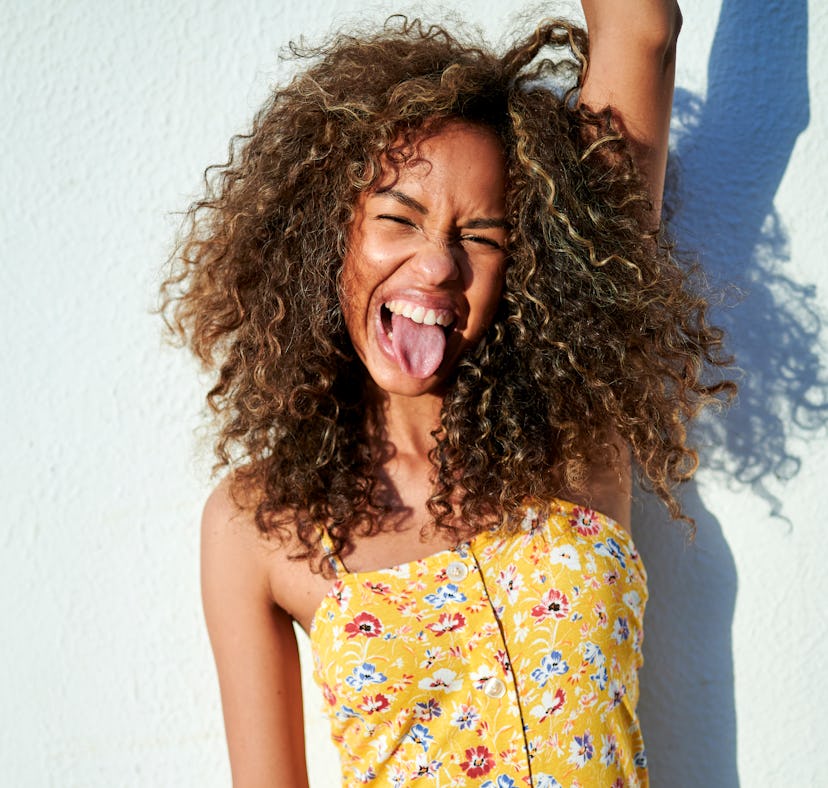 Portrait of woman sticking out tongue in front of white wall