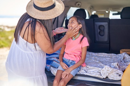 mother applying sunscreen to cheek of daughter at back of car, does sunscreen expire?