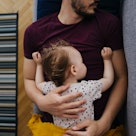 爸爸睡在沙发上，把孩子抱在胸前。