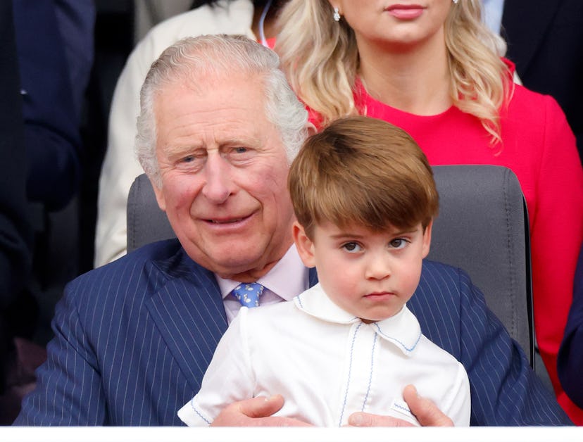 Prince Louis of Cambridge sits on his grandfather Prince Charles, Prince of Wales's lap as they atte...