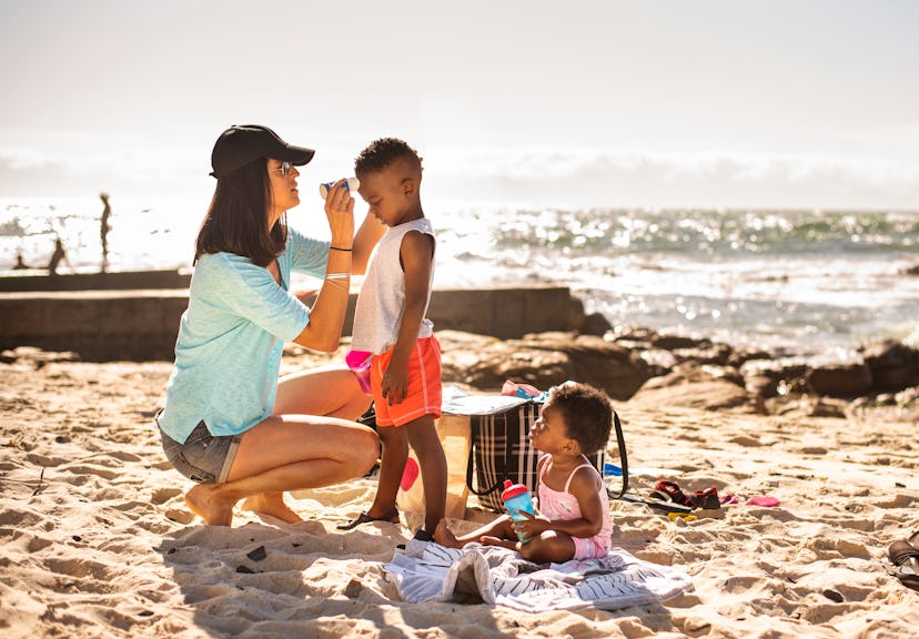 Mom putting suntan lotion on child at beach, does sunscreen expire?