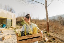 Photo of a young woman carrying a crate full of plants. Manifestations for june 2022 full strawberry...