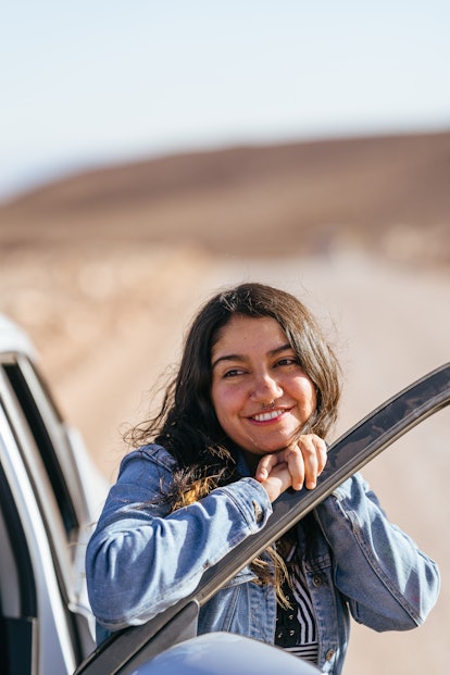 A straight ahead photo of a woman on a road trip is snapped with posing tips, according to professio...