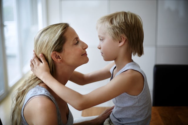 A blonde mom in her late 30s wearing a gray tank top and her blonde son holding each other