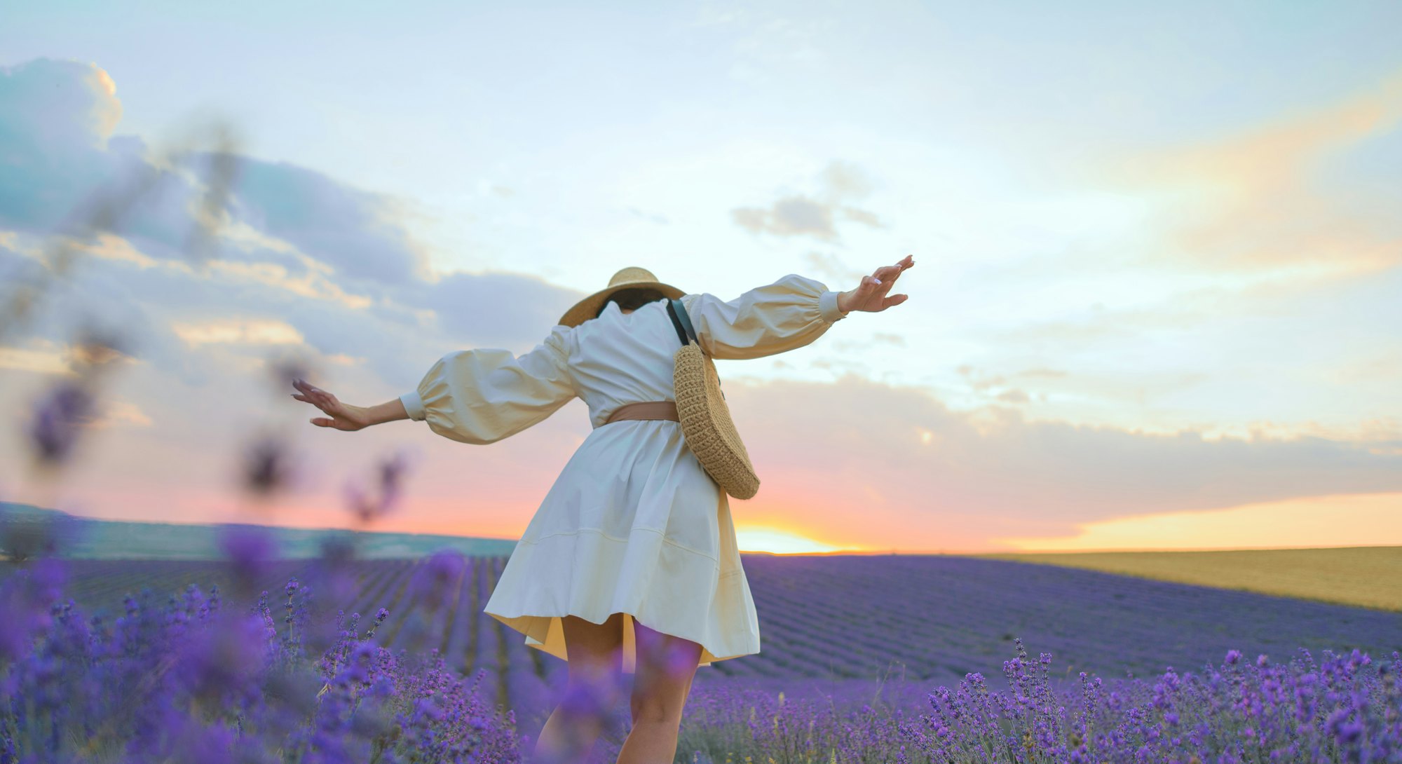 A young woman in a straw hat, an ivory dress and an eco-style handbag in lavender fields. Your do's ...
