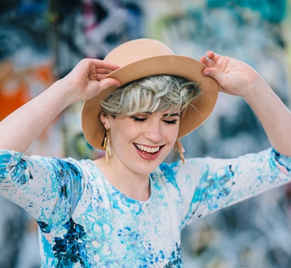 A woman poses in front of graffiti, which is how to pose for pictures.