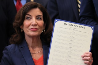 Gov. Kathy Hochul holds up signed legislation as she is surrounded by lawmakers during a bill signin...