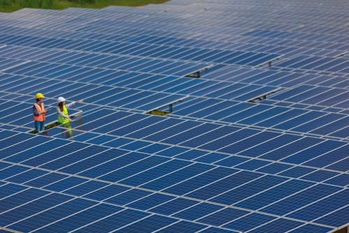 Two Asian maintenance engineer working in the solar farm with laptop and digital tablet.