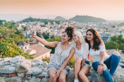 Happy friends taking photos on the mountain top. How the June 2022 full strawberry moon will affect ...