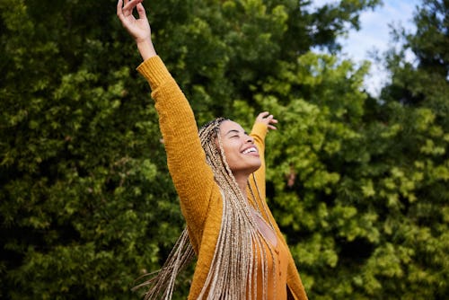 Carefree young woman with long braided hair standing outside in nature. These 3 zodiac signs will be...