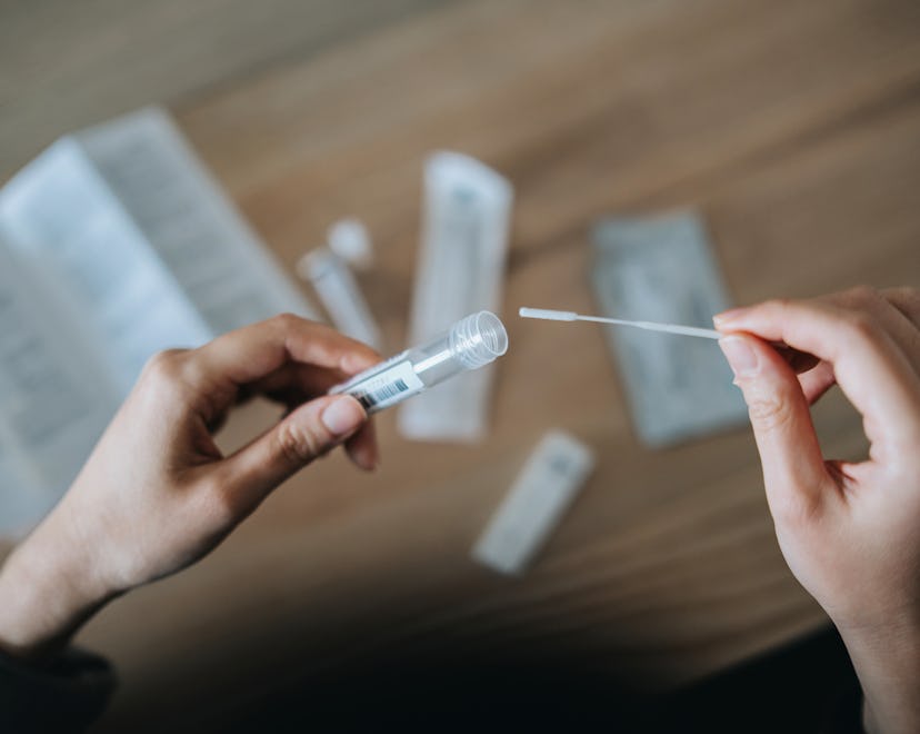 Two hands holding a throat swab Covid test kit
