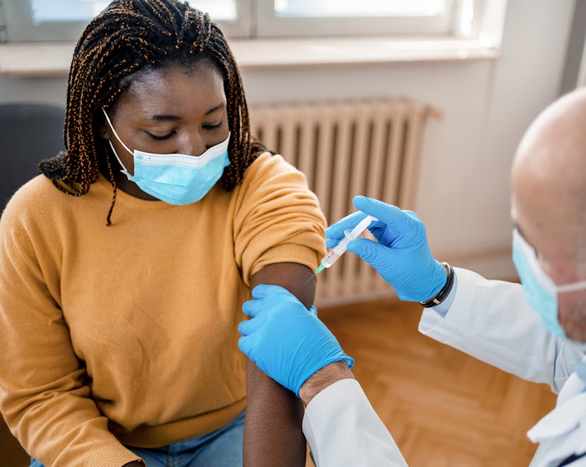 A woman getting a booster shot after Covid infection from a doctor in a medical office.