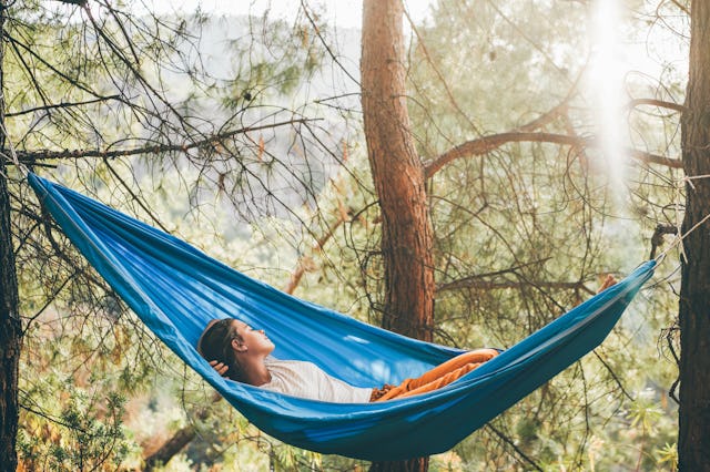 These backyard products are genius and will amp up your space. Pictured: a woman lying in a hammock.