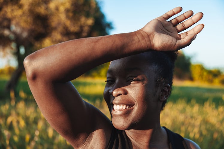 young woman blocks her face from the sun as she thinks about the 2022 summer solstice