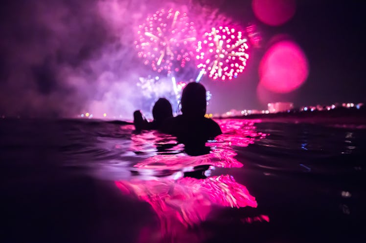 Group of girls on the Mataró festivity fireworks from inside water after reading their July 2022 mon...