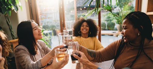 A group of friends is toasting together during a dinner party. The spiritual meaning of the june 202...