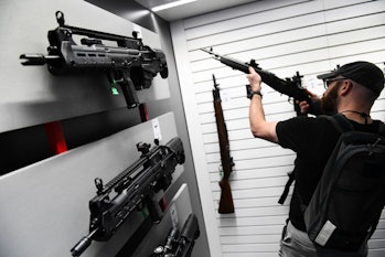 Springfield Armory Hellion bullpup rifles (L) are displayed as an attendee holds an M1A series rifle...