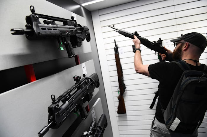 Springfield Armory Hellion bullpup rifles (L) are displayed as an attendee holds an M1A series rifle...