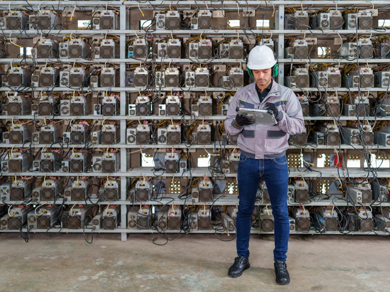 Professional engineers carrying the ltablet working in crypto mine. Crypto mine management software....