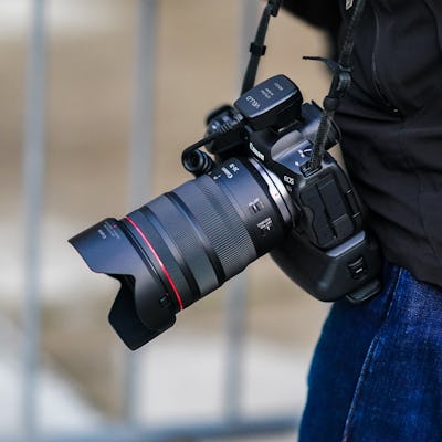 PARIS, FRANCE - OCTOBER 01: A photographer carries a Canon R5 mirrorless camera equipped with a TTL ...