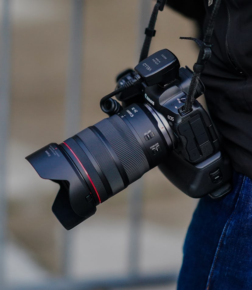 PARIS, FRANCE - OCTOBER 01: A photographer carries a Canon R5 mirrorless camera equipped with a TTL ...