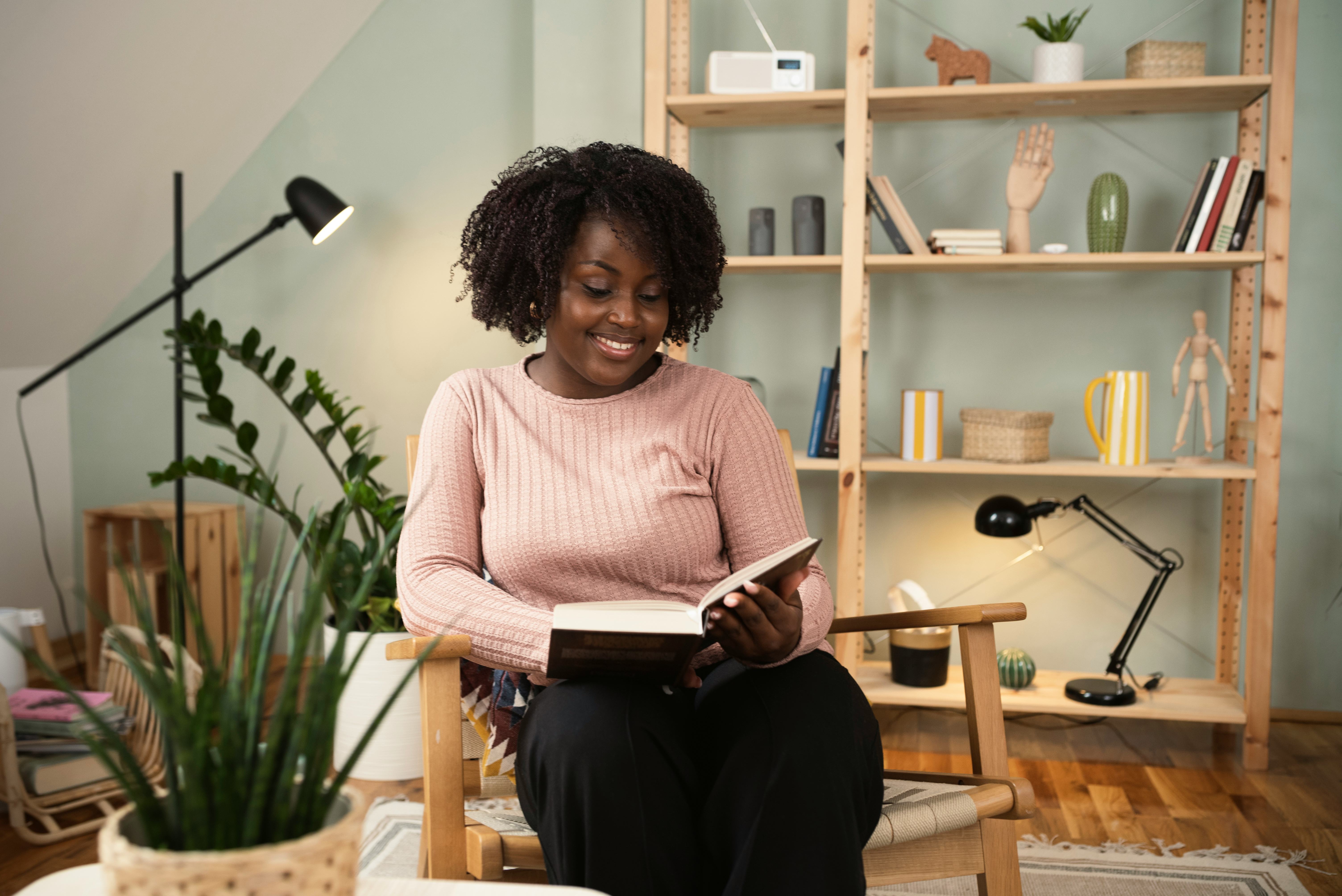 African American young woman reading a book and relaxing at home