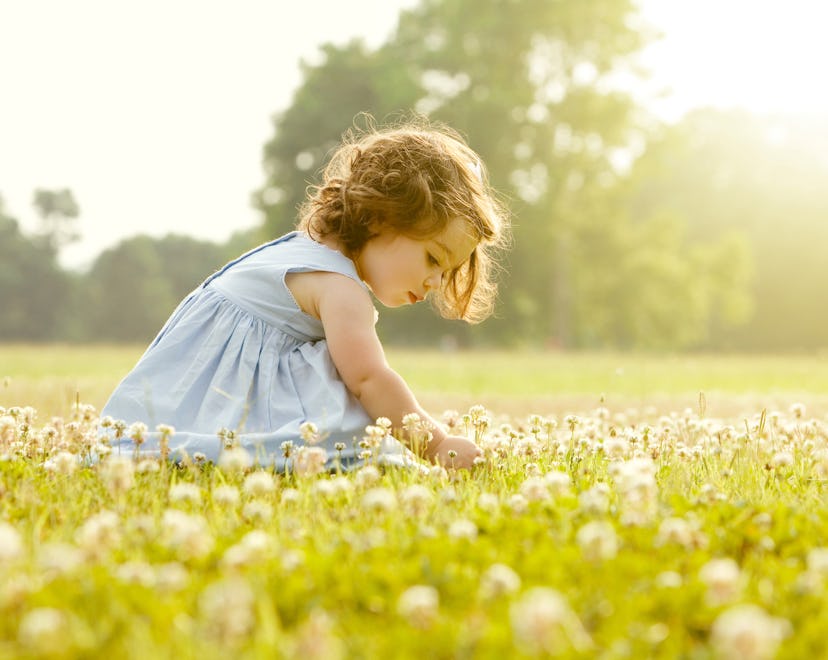 a little girl in a sunny flower meadow in an article about baby girl names that start with "M"