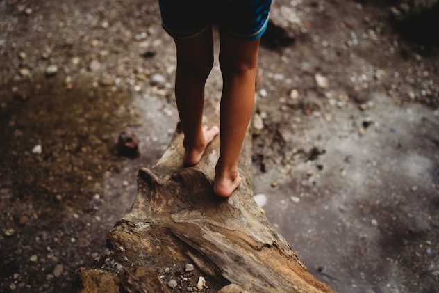 child's feet on a log in the woods in an article about why your kid gets so many mosquito bites