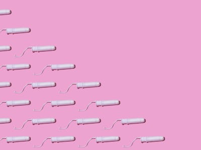 Cellulose white tampon pattern with twine, on the left side, on pink background. Concept of menstrua...