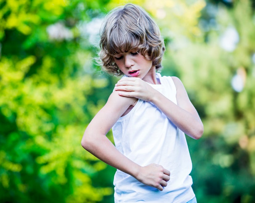 Young boy scratching arm.