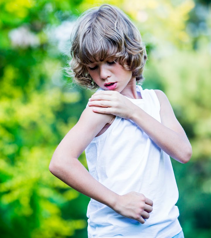 Young boy scratching arm.