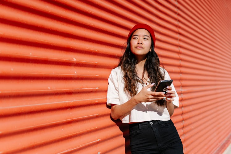 young woman checks emails on her phone as she gears up for the july 13, 2022 full moon in capricorn