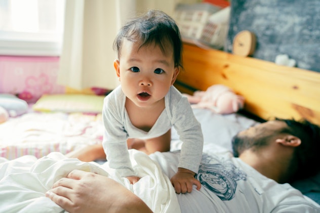 Baby crawling around in bed with dad in an article about baby names that start with P