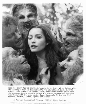 Five creature with hair covering their faces and heads are crowded around Barbara Carrera in a scene...